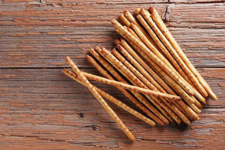 Crispy bread straw on old wooden background, top view with copy space