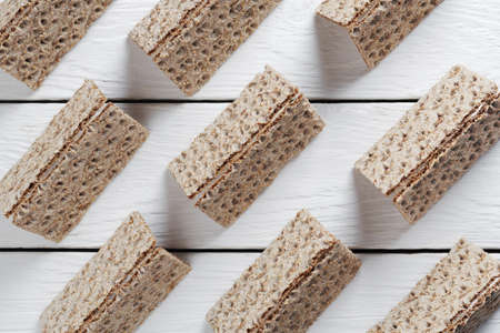 Rye crispy bread with seeds on white wooden background or table, top view