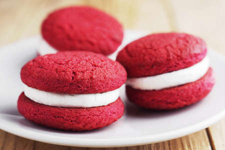 Red velvet whoopie pies on a plate on wooden table close upの写真素材