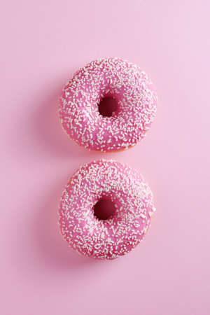 Two donut with sprinkles on pink background, top viewの写真素材