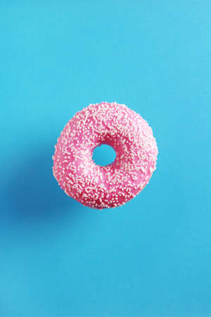 Sweet pink donut with sprinkles on blue background, top viewの写真素材