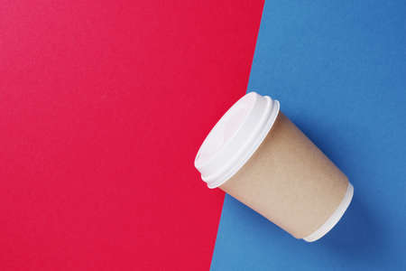 Disposable paper cup with lid for coffee and tea on a bright blue-red background, top view with space for textの写真素材