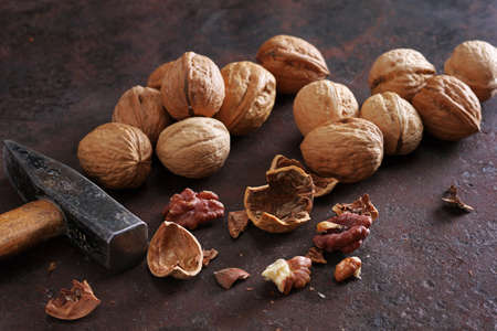 Whole and cracked walnut with a hammer on rusty metal background