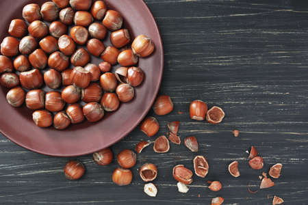 Hazelnuts in a brown plate on a black wooden background, top viewの写真素材