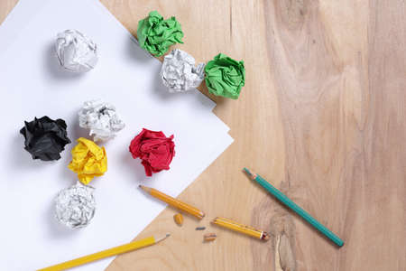 High angle view of crumpled paper balls, empty sheet and broken pencils on wooden backgroundの写真素材