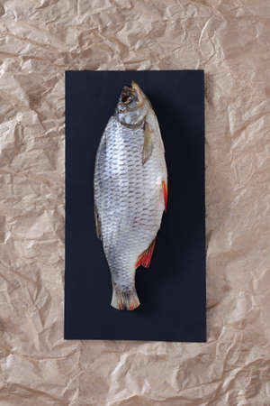 Salted dried fish on crumpled paper background, top view