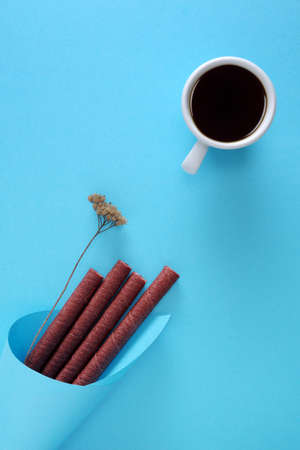 Chocolate wafer sticks and cup of coffee on blue background, top viewの写真素材