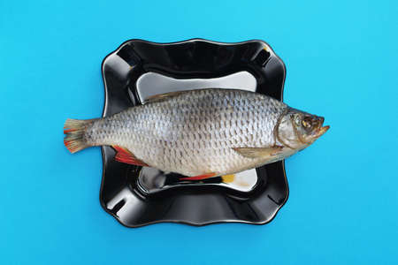 Salted-dried fish on a black plate on blue background, top view