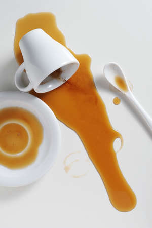 Spilled cup of coffee on white table shot from aboveの写真素材