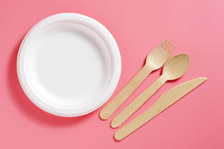 Paper plate with wooden cutlery on pink background, top viewの写真素材