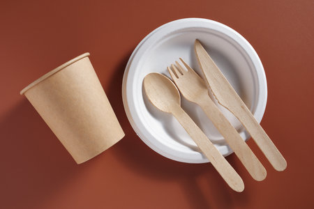 Disposable eco-friendly dishes on brown background, top viewの写真素材
