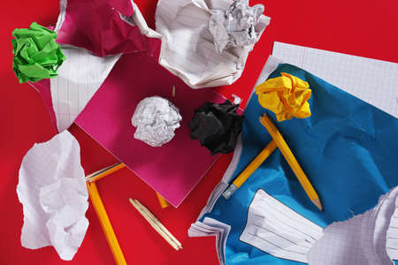 Torn school notebook and broken pencils on red background, top view