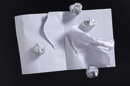 Torn school notebook and crumpled paper balls on black background, top viewの写真素材