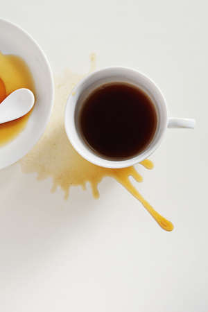 Spilled cup of coffee on white table, top view