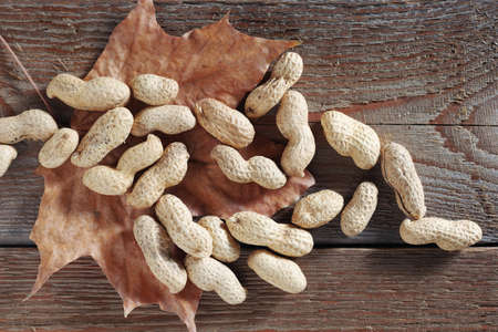 Heap of peanuts on old wooden background, top view