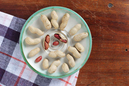 Peanuts in plate on the table, top view