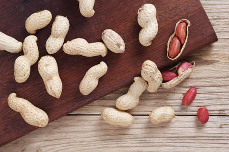 Heap of peanuts on old wooden background, top view