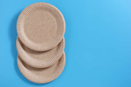 Disposable brown paper plates on a blue background, top view with copy spaceの写真素材