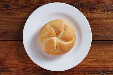 Loaves of small wheat bread on a plate on wooden background, top viewの写真素材