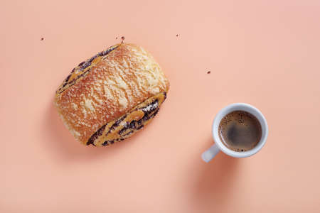 Sweet bun with poppy seeds and cup of coffee on color background, top viewの写真素材