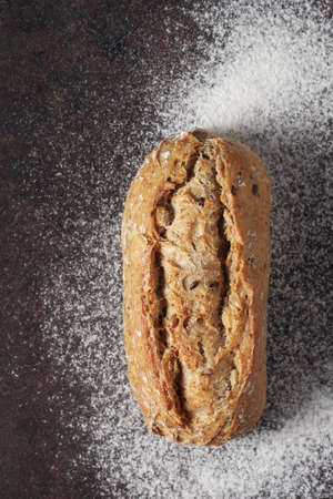 Loaf of small bread on metal with flour background, top view