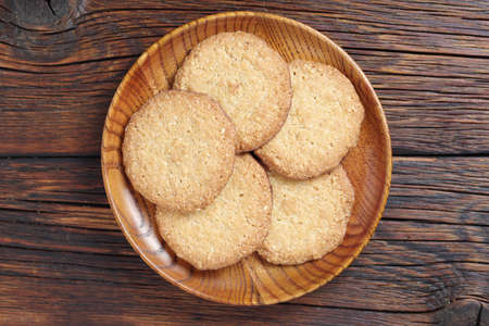 Delicious oat cookies in wooden plate on the old table, top view