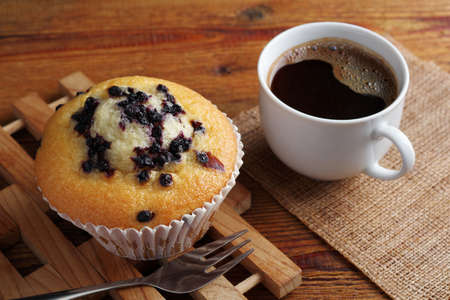 Cupcake with blueberry and cup of coffee on wooden tableの写真素材