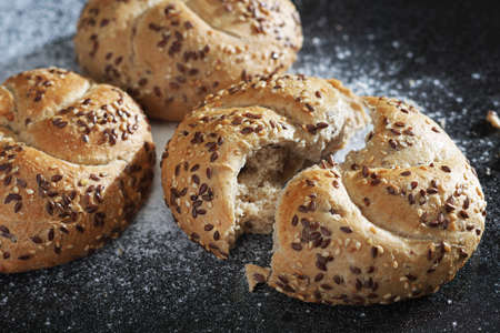 Bread rolls with flax-seeds on black metal tray close-upの写真素材