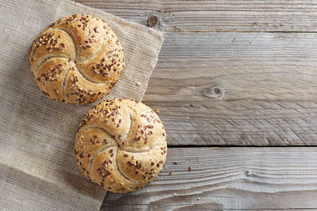 Small bread with flax-seeds on wooden background, top view with copy spaceの写真素材