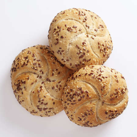 Loaves of small bread with flax-seeds on white background, top view