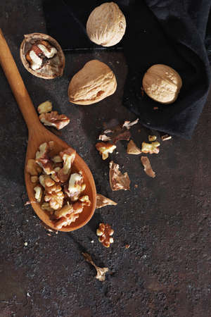 Walnuts in wooden spoon and near on grunge metal background, top view