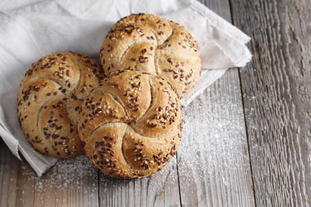 Freshly baked buns with flax-seeds on the rustic wooden table