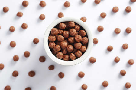 Chocolate corn balls in bowl on white background, top view