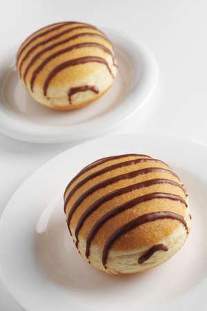 Donuts with chocolate on a plate on white background close-upの写真素材