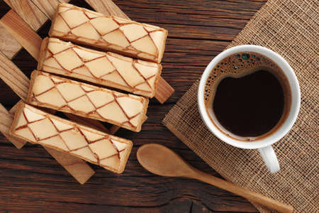 Glazed puff pastry "Sfogliatine Glassate" and cup of coffee on wooden background, top viewの写真素材