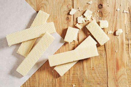 Whole and broken wafers on old wooden background, top viewの写真素材