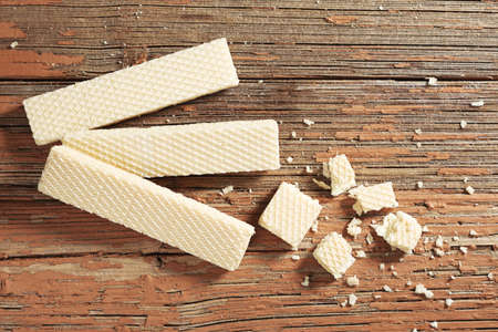Vanilla wafer biscuit whole and broken on old wooden background, top view