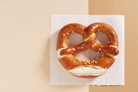 Freshly baked Bavarian pretzel with salt on two color background, top view with copy spaceの写真素材