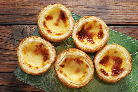 Pastel de Nata on a green ceramic board on the table, top view. Traditional portuguese pastry