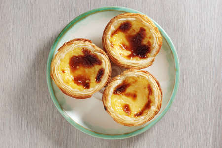 Typical Portuguese custard pies - Pastel de Nata on a plate on the table, top view