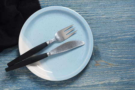 Empty plate with cutlery on old blue wooden table, top view with copy spaceの写真素材