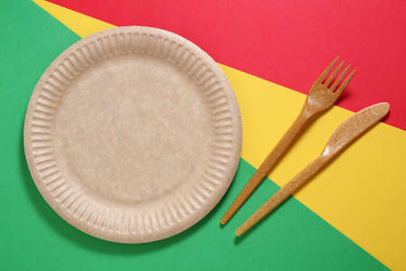 Biodegradable brown colored craft plate and wood fiber cutlery on colored background, top viewの写真素材