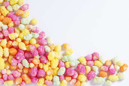 Rainbow colored puffed maize and rice confectionery on a white background, top view with copy space