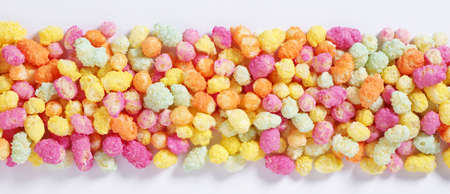 Rainbow colored puffed maize and rice confectionery on a white background, top view