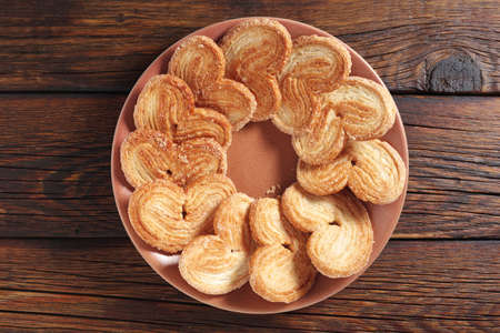 Puff pastry cookies in the shape of a heart in plate on wooden background, top viewの写真素材