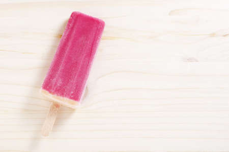 Ice cream on stick on wooden background, top view with copy space
