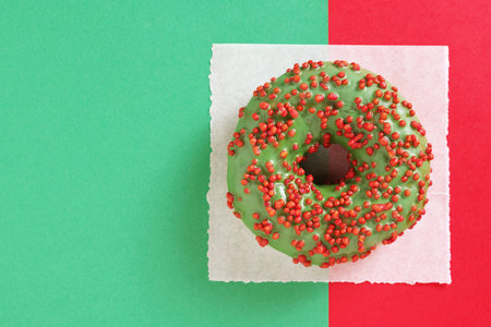 Donut with green icing on two-color background, top view with copy spaceの写真素材
