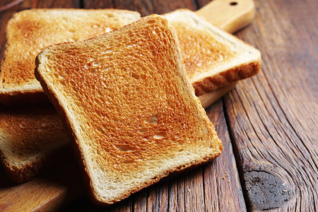 Slices of toasted bread on kitchen board on wooden table close upの写真素材
