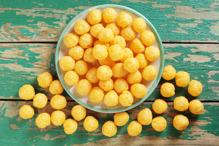 Puff cheese balls on a plate on old green wooden background, top view