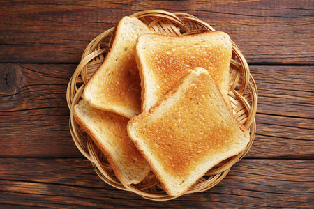 Toasted bread on a wicker plate on wooden background, top viewの写真素材